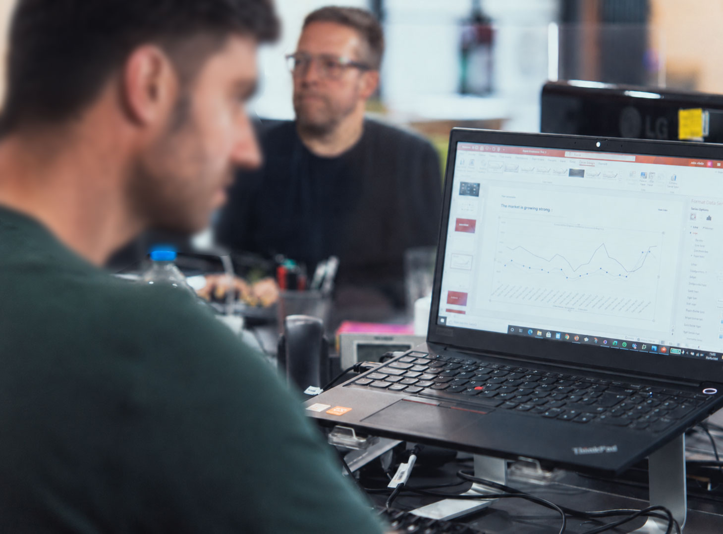 Two Vivid colleagues, one reviewing website performance and analytics on a laptop in the Vivid office.